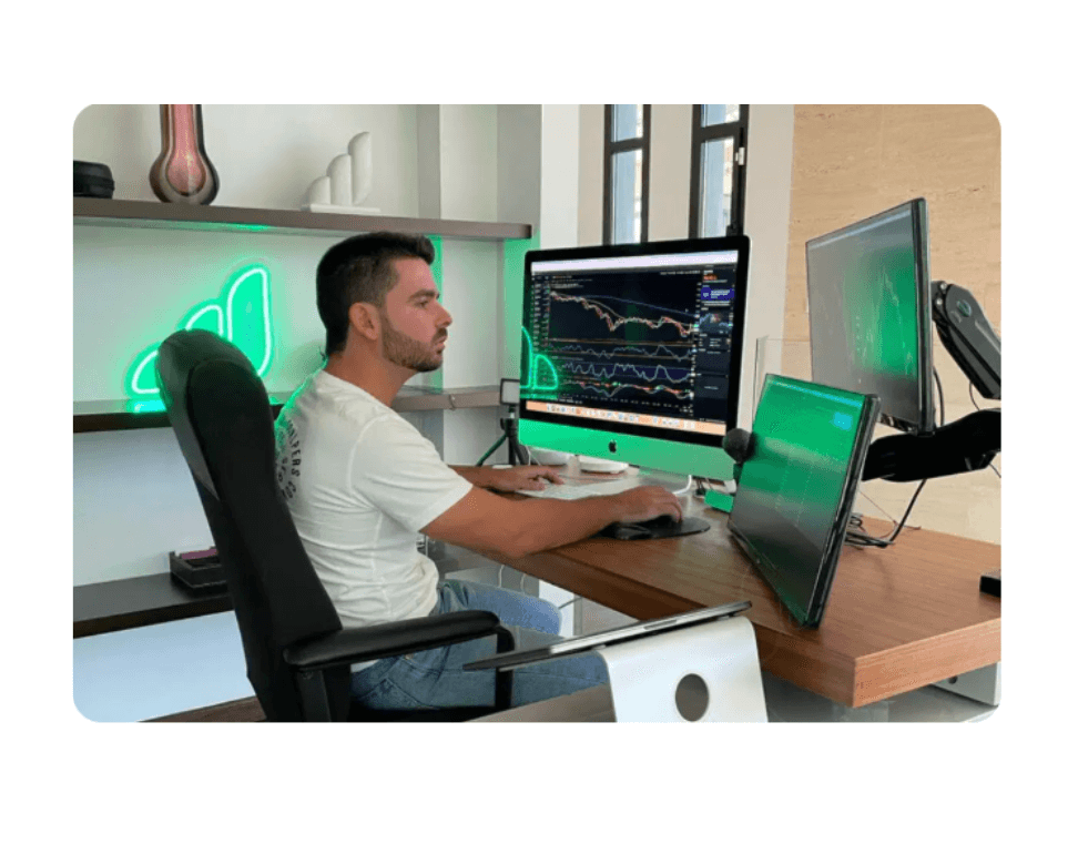 Persona trabajando en una estación de trading con varios monitores mostrando gráficos financieros